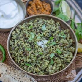 Urad dal khichdi served in a bowl and served with yogurt, pickle and papad.
