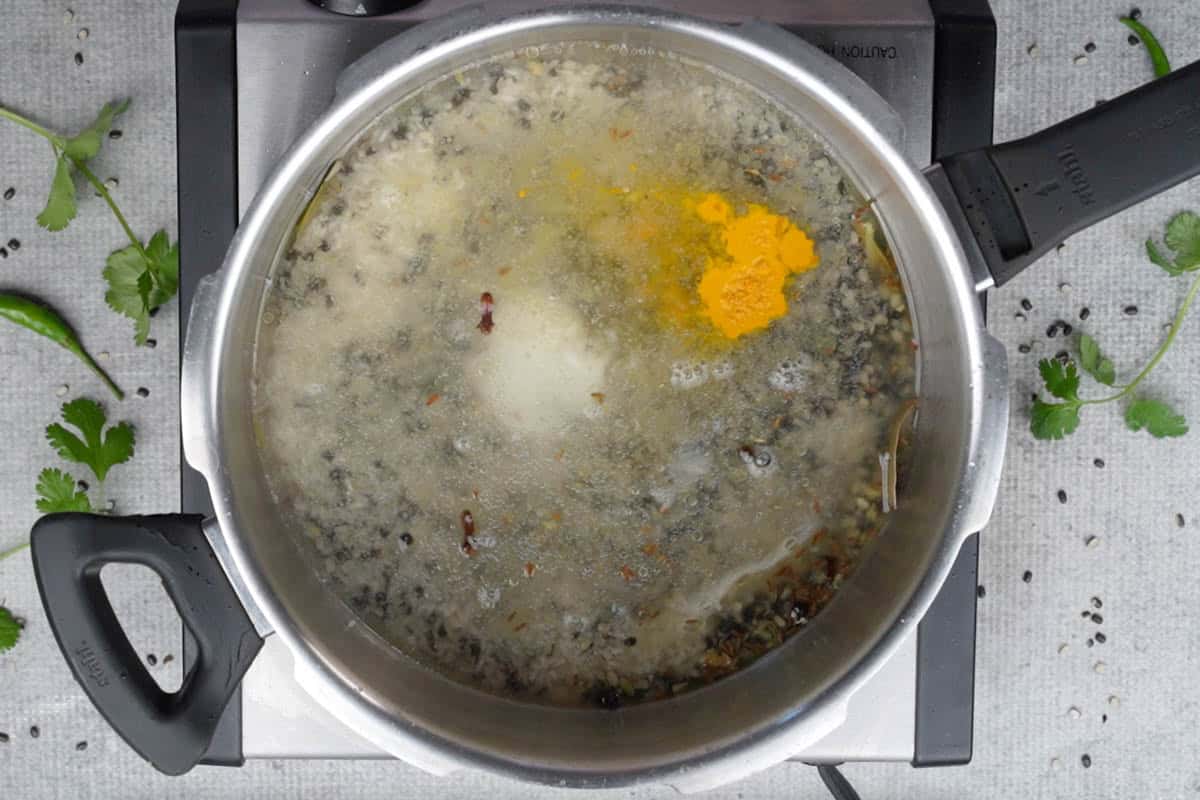Urad dal, rice, turmeric powder, salt and water added to the cooker.