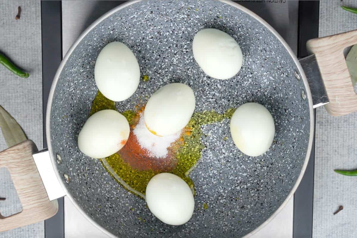 Slit eggs added to a pan with oil, turmeric power, chili powder and salt.
