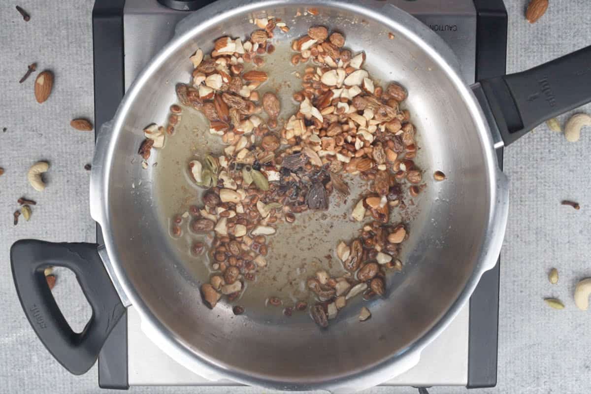 Green cardamom, black cardamom and cloves added to the cooker.