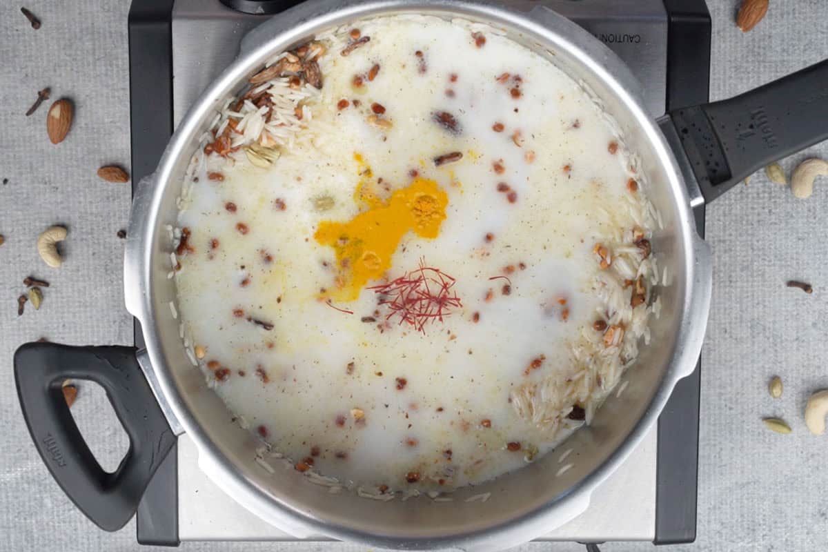 Water, milk, turmeric powder and saffron added to the cooker.