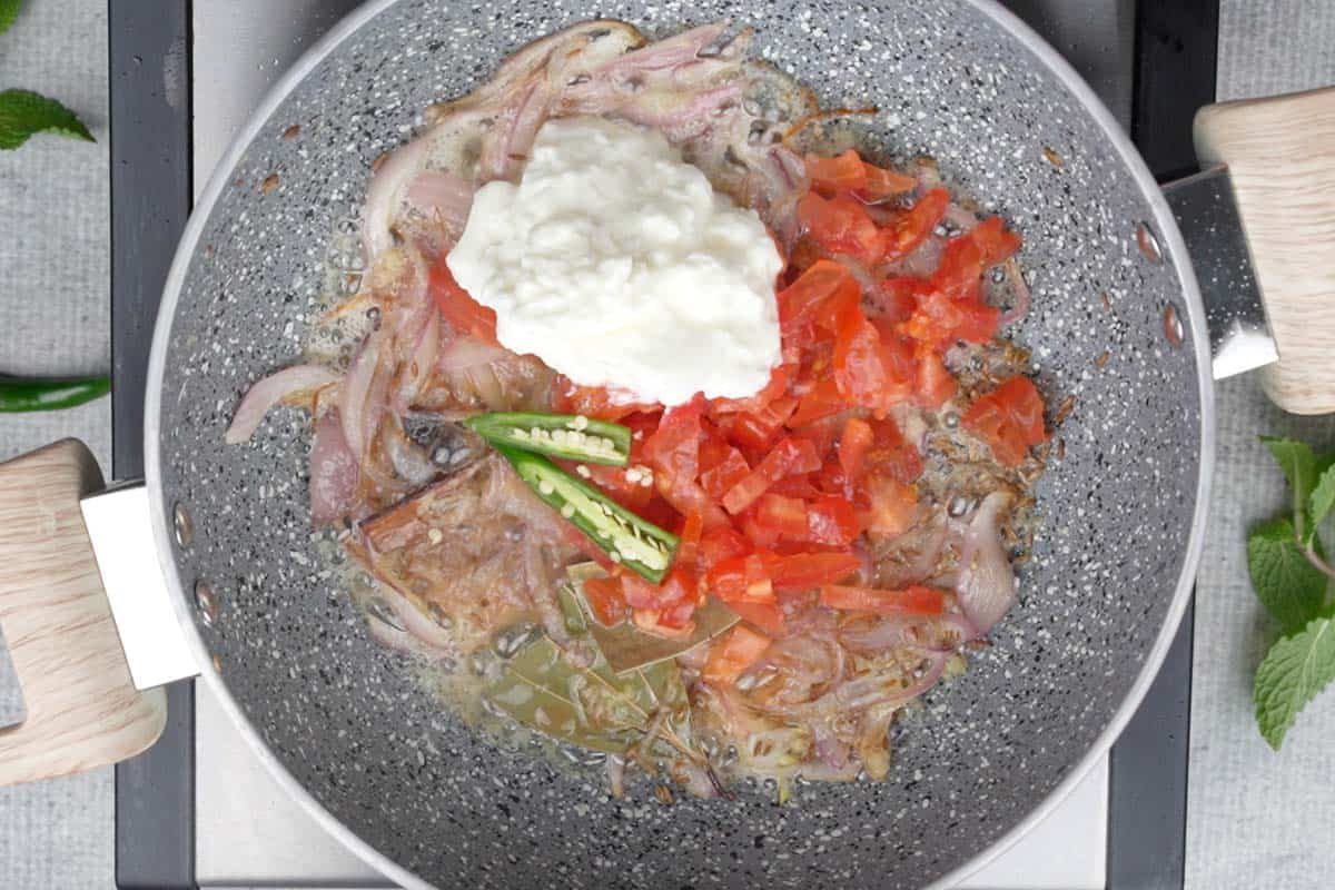 Tomatoes, yogurt and green chilies added to the pan.