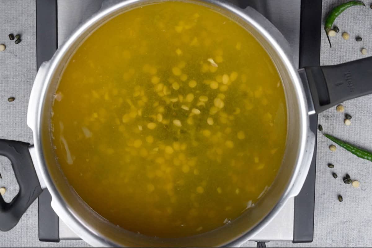 Soaked lentils, ginger, garlic, salt and turmeric powder added to a pressure cooker along with water.