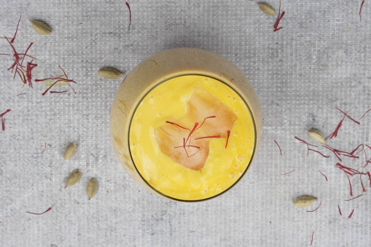 Mango lassi poured in a glass and garnished with saffron.