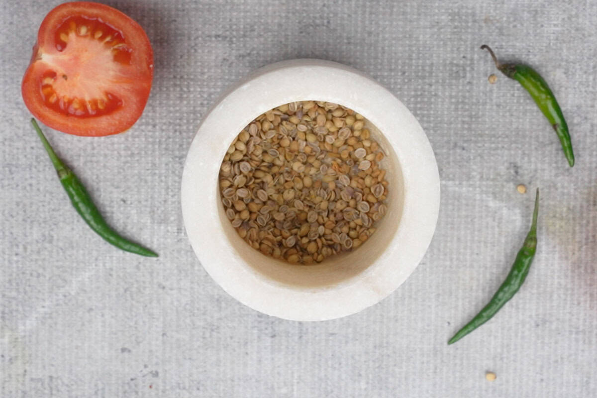Crushed coriander and fenugreek seeds in a mortar pestle.