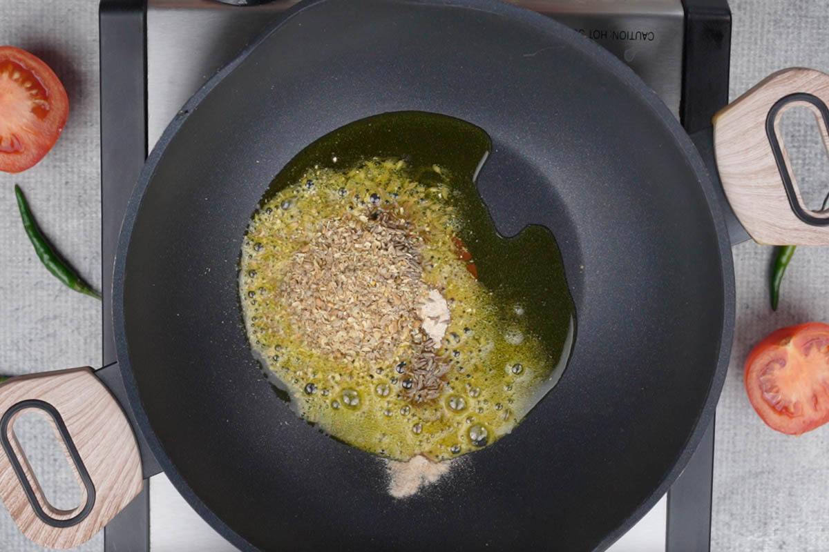 Hing, cumin seeds, coriander fenugreek seeds powder added to hot oil in a pan.