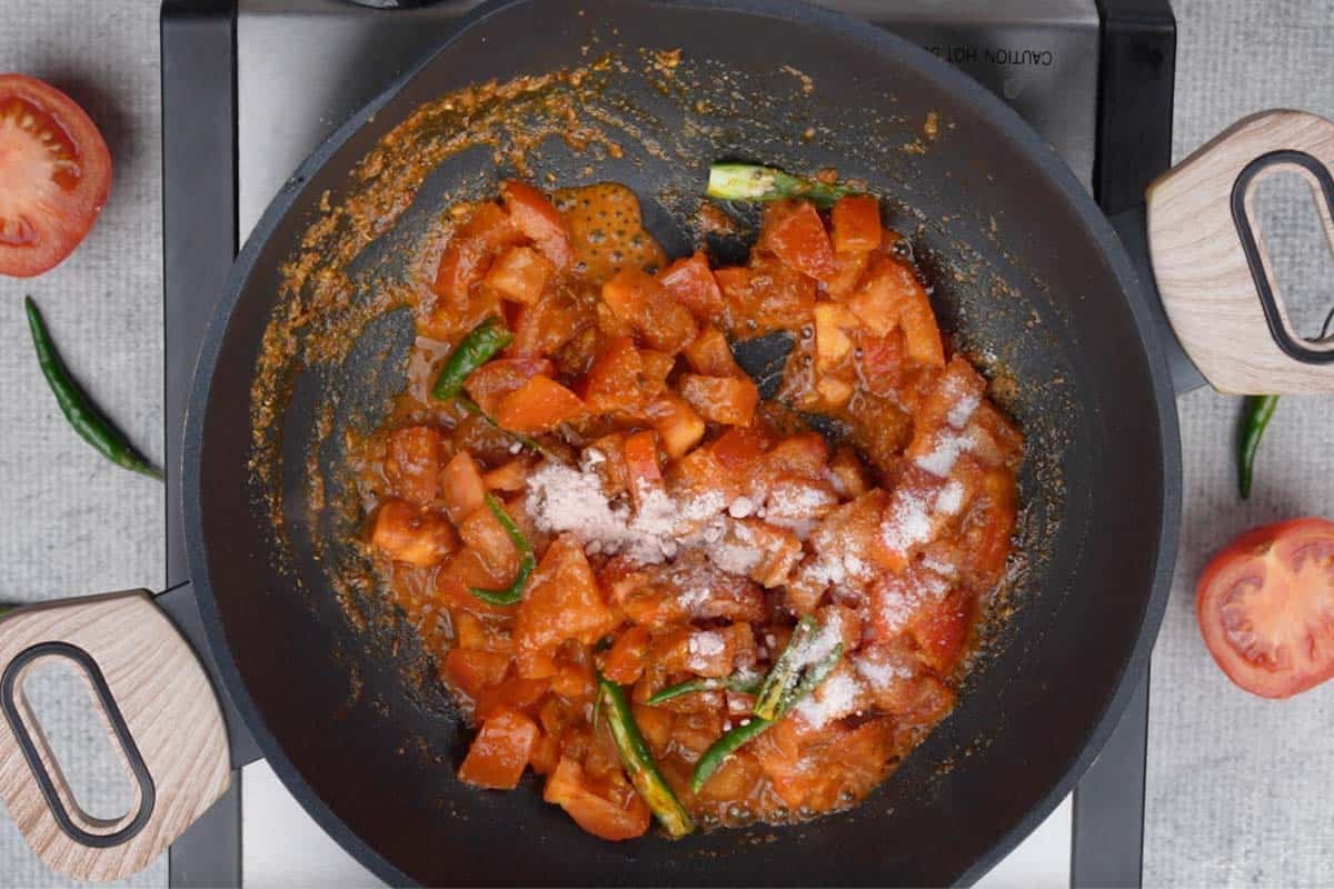 Tomatoes, green chilies, black salt and regular salt added to the pan.