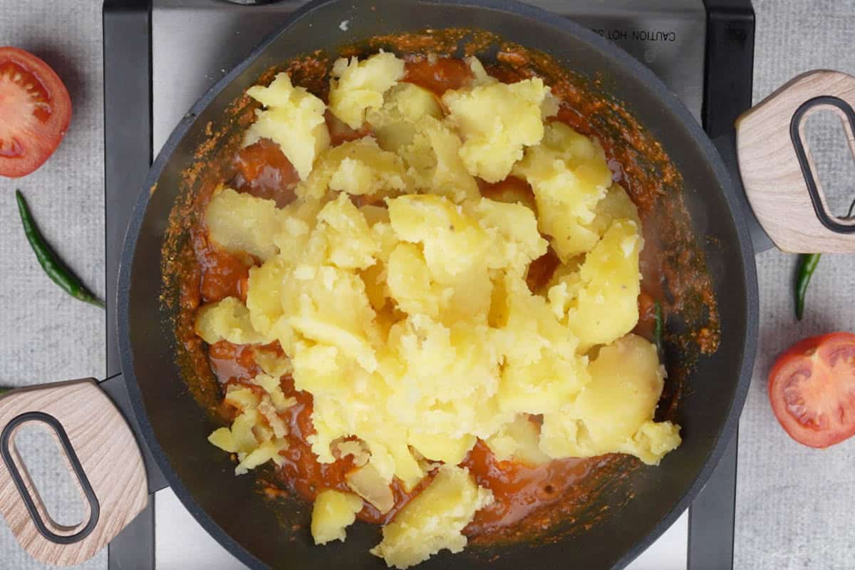 Boiled potatoes crushed with hands and added to the pan.