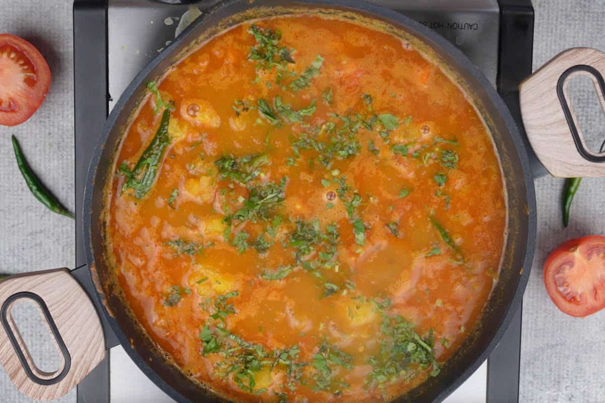 Ready aloo tamatar ki sabji garnished with chopped cilantro.