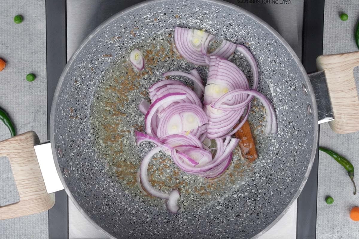 Sliced onions added to the pan.