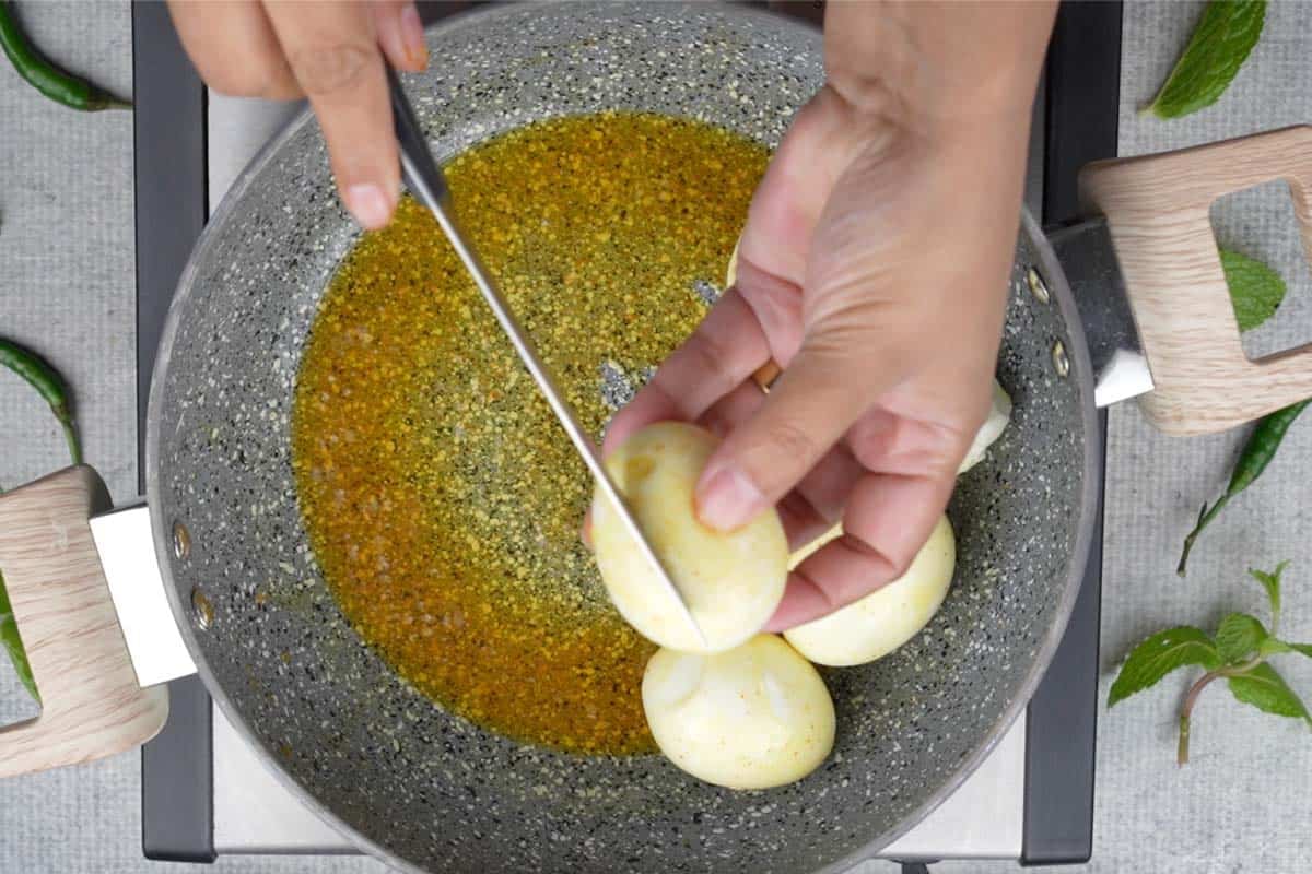 Making slits in boiled egg using a knife.