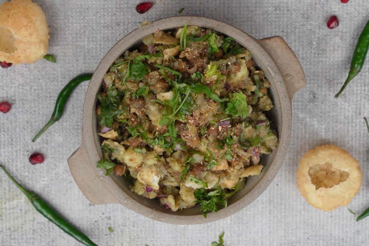 Ready churmur chaat garnished with cilantro, pomegranate seeds and crushed puchkas.