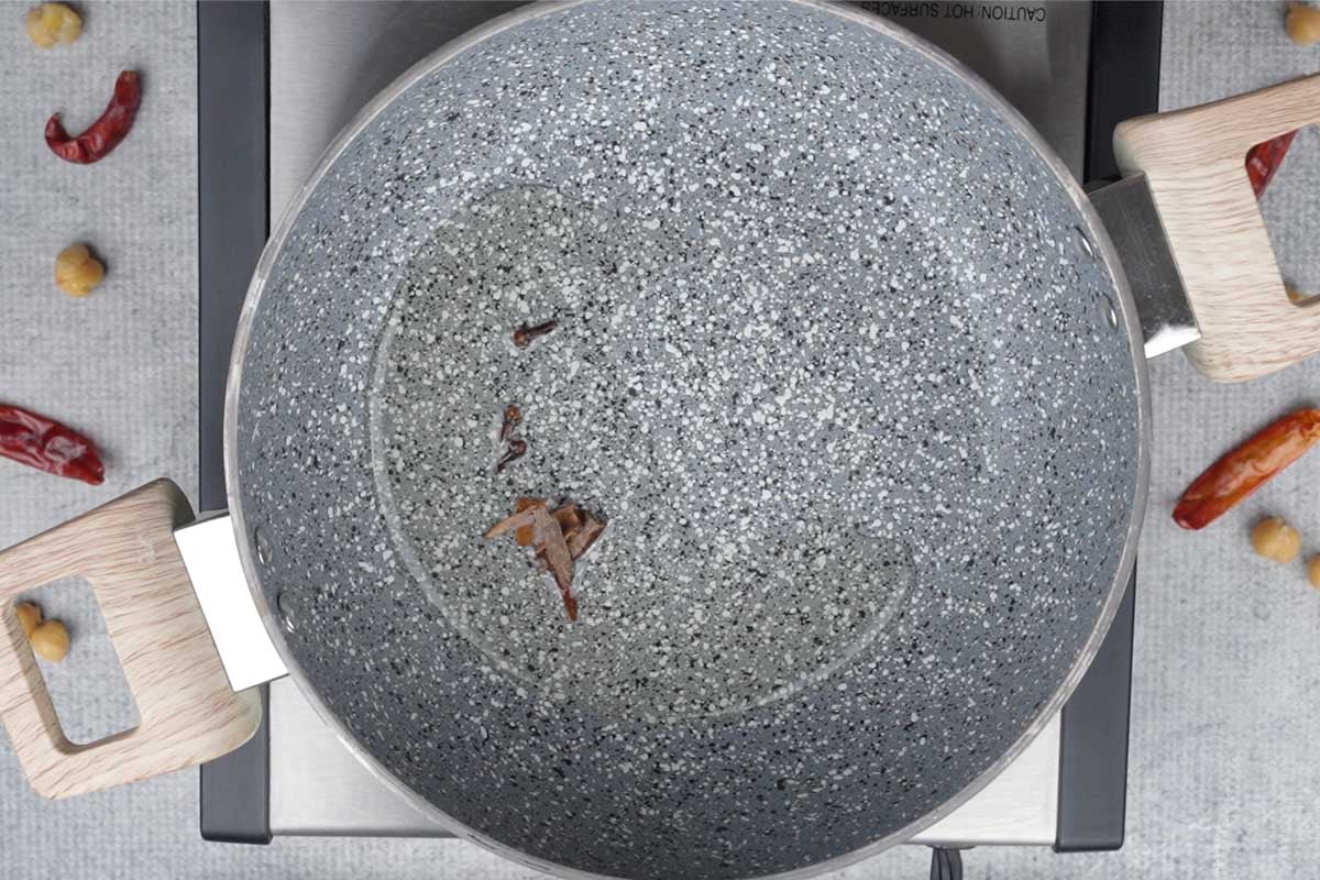 Whole spices added to hot oil in a pan.