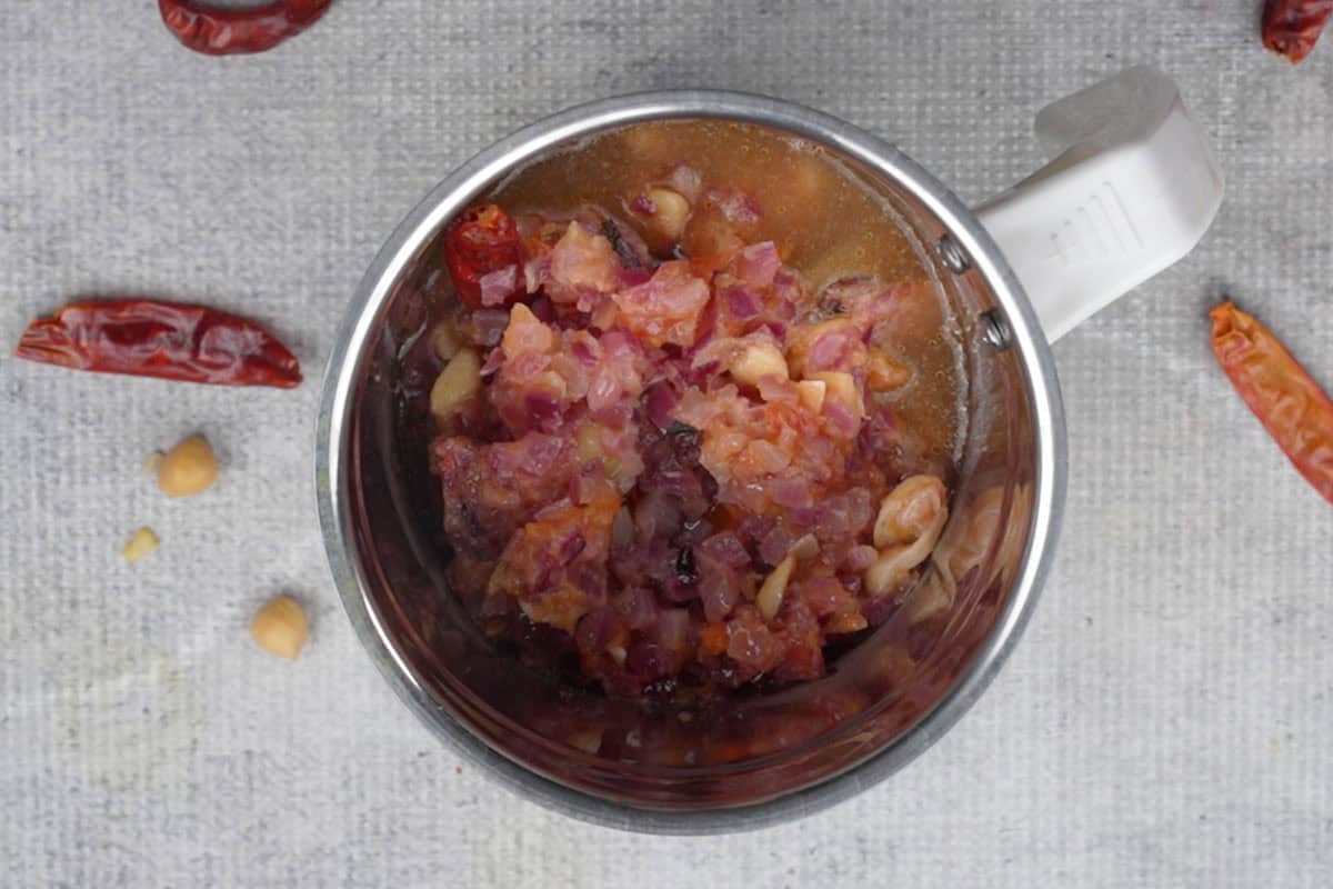 Cooked onion tomato mixture added to a blender with water.