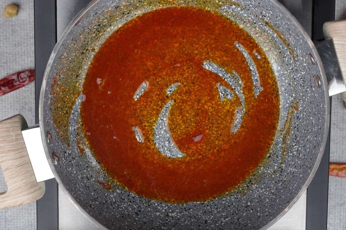 Kashmiri red chili powder added to hot oil in a pan.
