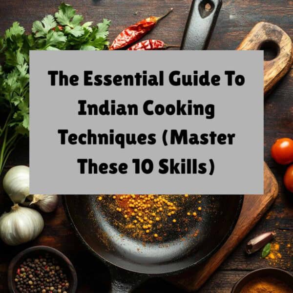 A cast iron pan surrounded by colorful spices, herbs, garlic, and chili peppers. Text overlay reads: The Essential Guide to Indian Cooking Techniques (Master These 10 Skills). Discover key Indian cooking techniques for authentic flavor.
