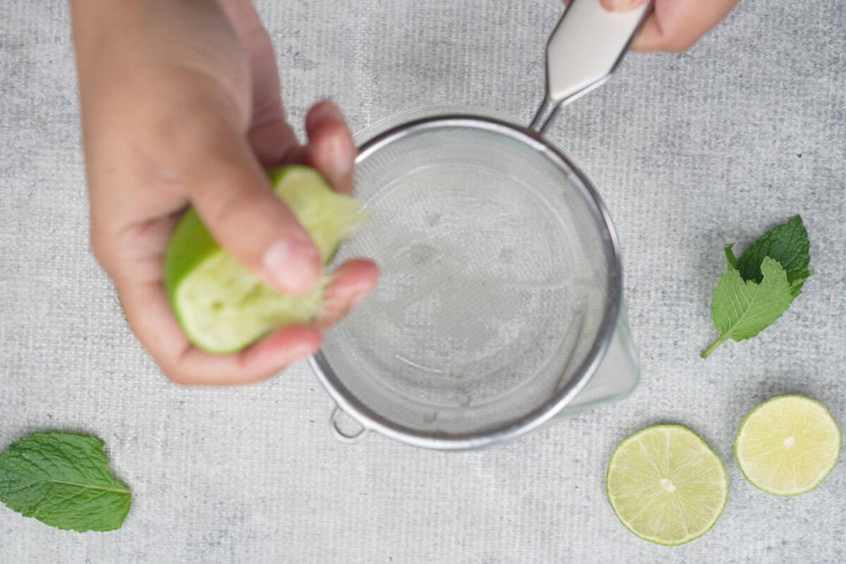 Squeezing lime juice through a strainer.