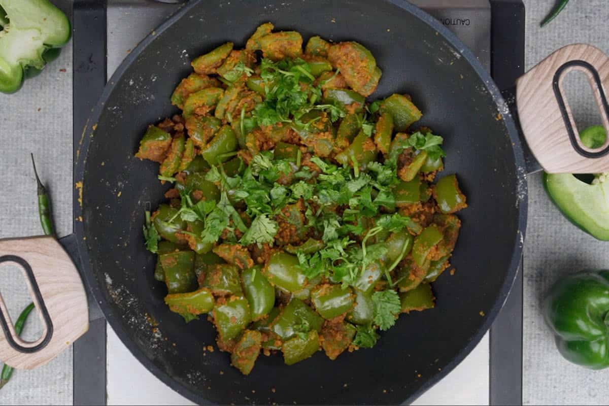 Ready capsicum besan sabji garnished with chopped cilantro.