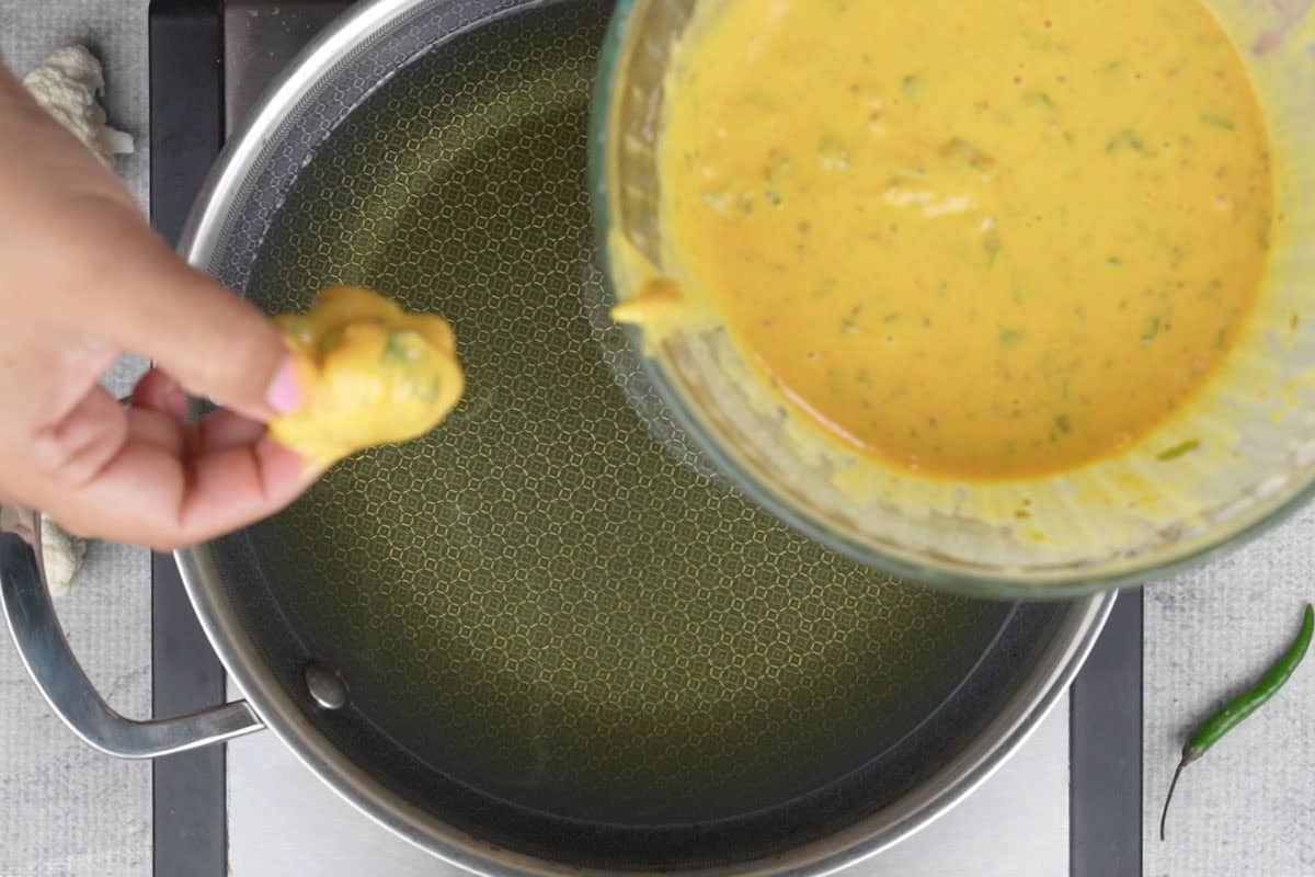 One gobi floret dipped in the batter and ready to be fried.