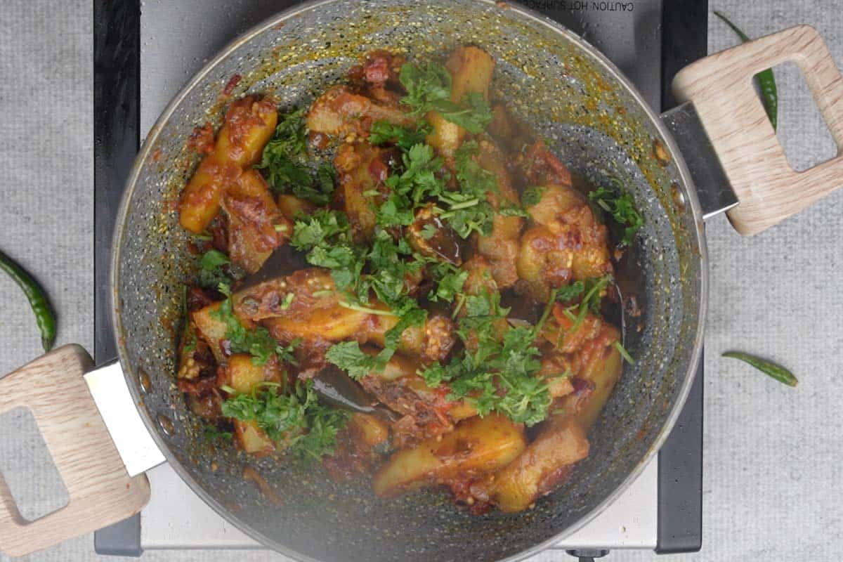 Ready aloo baingan garnished with chopped cilantro.