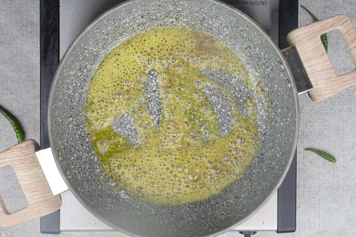 Cumin and hing added to hot oil in the pan.