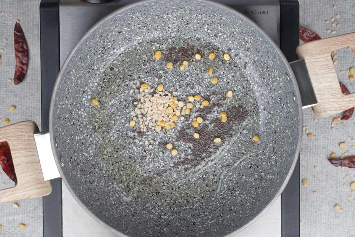Mustard seeds, chana dal and urad dal added to hot oil in a pan.