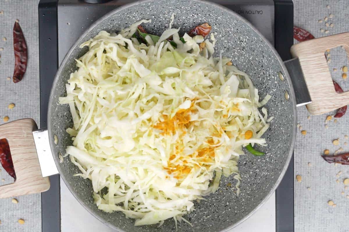 Cabbage and turmeric powder added to the pan.