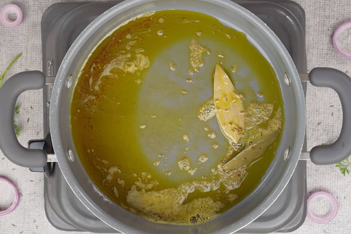 Cumin seeds and bay leaves added to hot oil.