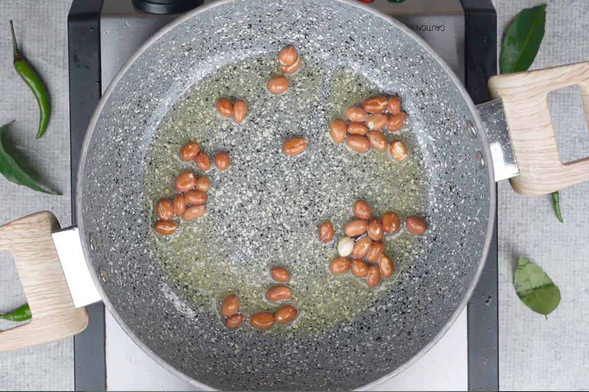 Peanuts fried in ghee in a pan.